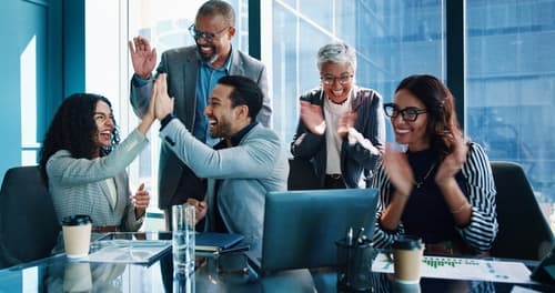 Diverse team celebrating success together in a bright modern office.